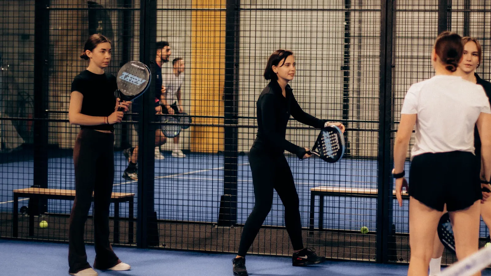 Four players warming up on an indoor padel court before a match